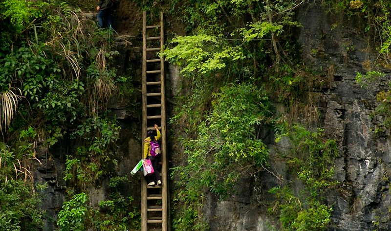 Neste vilarejo no sul da China, crianças devem subir por esta instável escada de madeira até chegarem à escola | Foto: YetTrue.