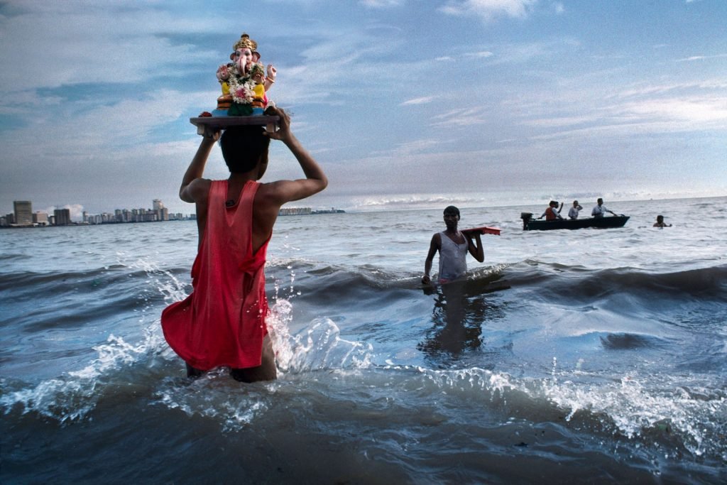 Um devoto carrega uma estátua do Deus Ganesh no Mar da Arábia durante um ritual de imersão fora da praia de howpatty. Mumbai - 1993
