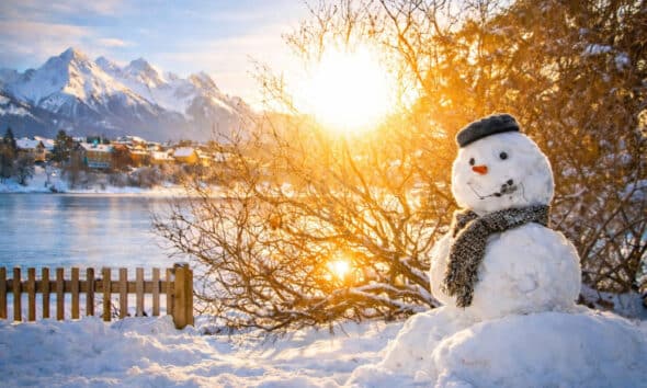 Boneco de neve em paisagem de inverno com montanhas ao fundo, cenário típico de destinos onde contratar seguro viagem para neve é recomendado.