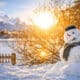 Boneco de neve em paisagem de inverno com montanhas ao fundo, cenário típico de destinos onde contratar seguro viagem para neve é recomendado.